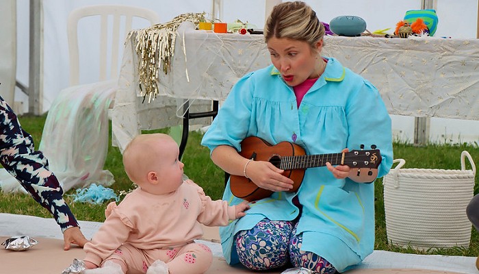 woman playing a guitar with a baby next to her