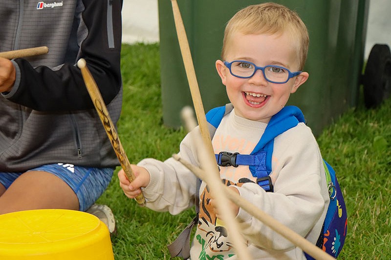 plentyn yn taro bwcad y defnyddio drum sticks